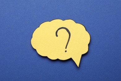Photo of Paper speech bubble with question mark on blue background, top view