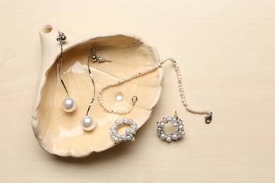Photo of Seashell with luxury jewelry on wooden background, flat lay
