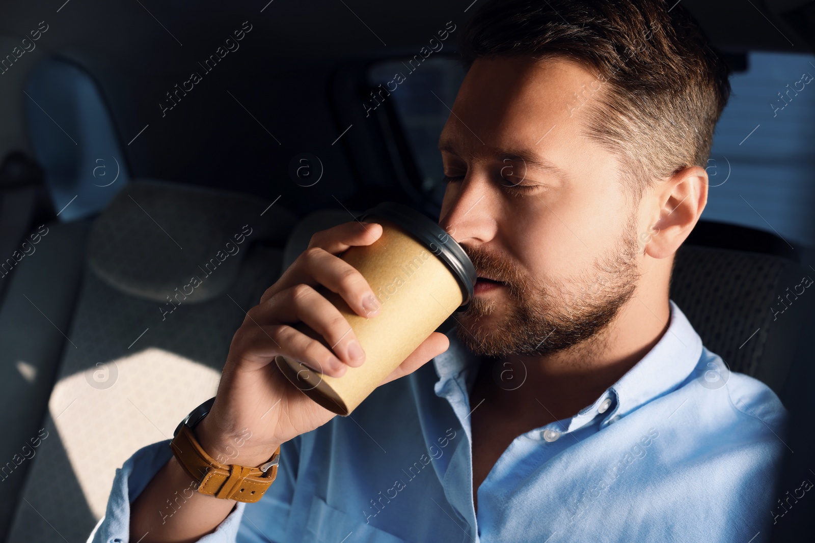 Photo of To-go drink. Handsome man drinking coffee in car