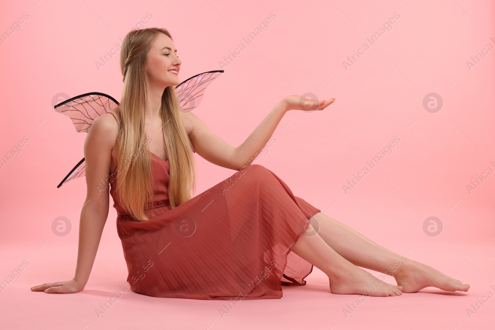 Photo of Beautiful girl in fairy costume with wings on pink background