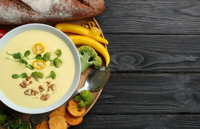 Photo of Flat lay composition with bowl of cheese cream soup and broccoli on black wooden table, space for text
