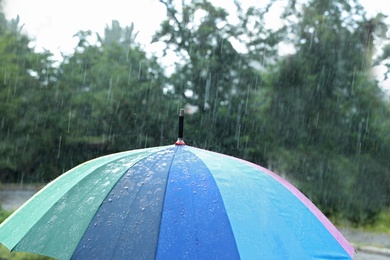 Photo of Open colorful umbrella outdoors on rainy day