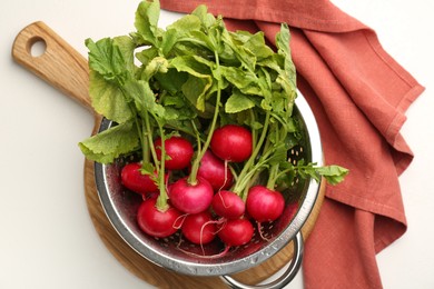 Photo of Wet radish in colander on white table, top view