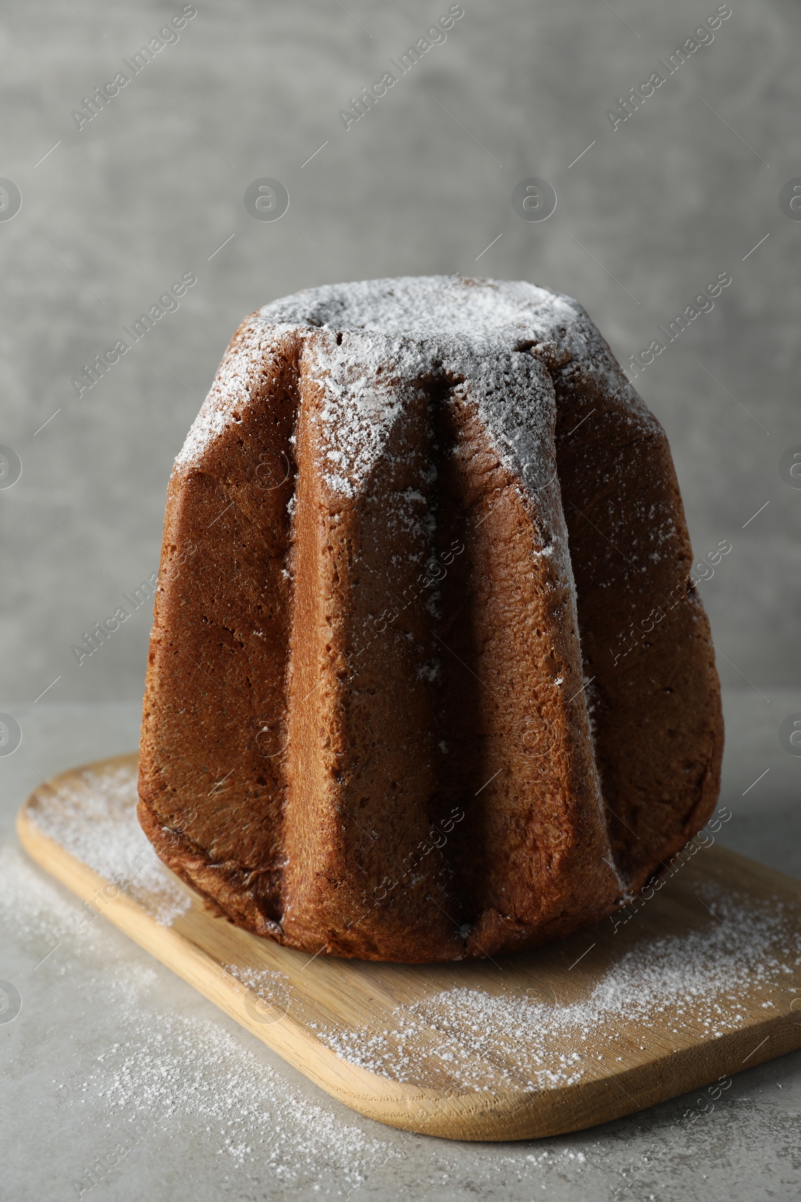 Photo of Delicious Pandoro cake decorated with powdered sugar on light grey table. Traditional Italian pastry