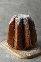 Delicious Pandoro cake decorated with powdered sugar on light grey table. Traditional Italian pastry