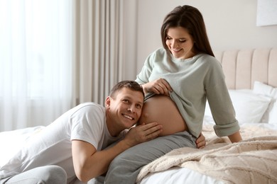 Photo of Young pregnant woman with her husband in bedroom