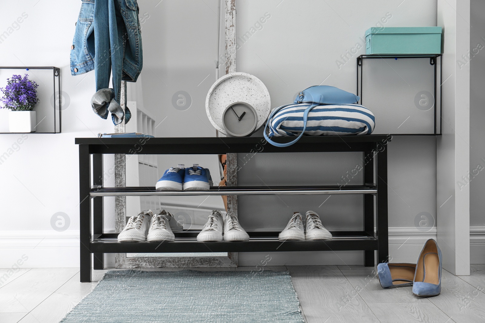 Stylish hallway interior with shoe rack and rug Photo of Stylish hallway interior with shoe rack and rug