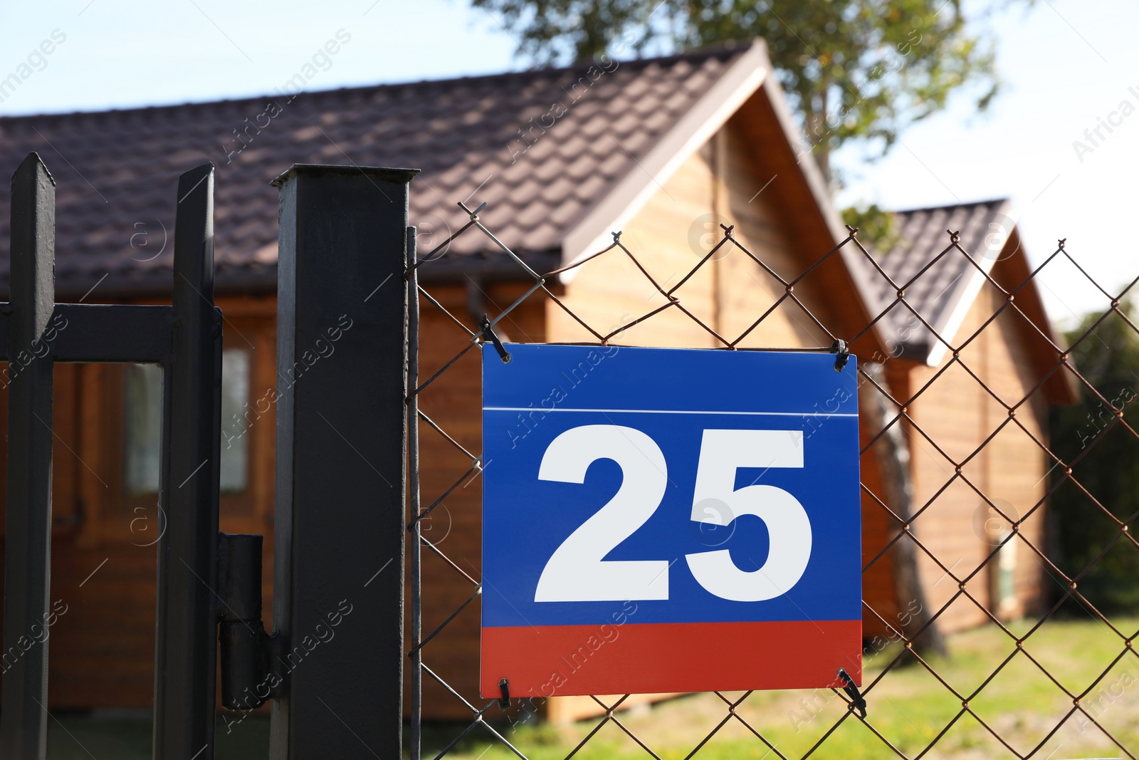 Photo of Plate with number twenty five hanging on fence near houses outdoors