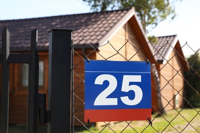 Photo of Plate with number twenty five hanging on fence near houses outdoors