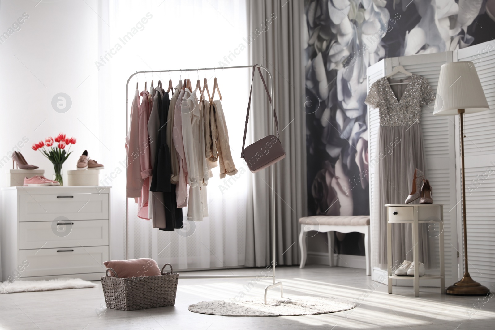 Photo of Rack with stylish women's clothes and handbag indoors. Interior design