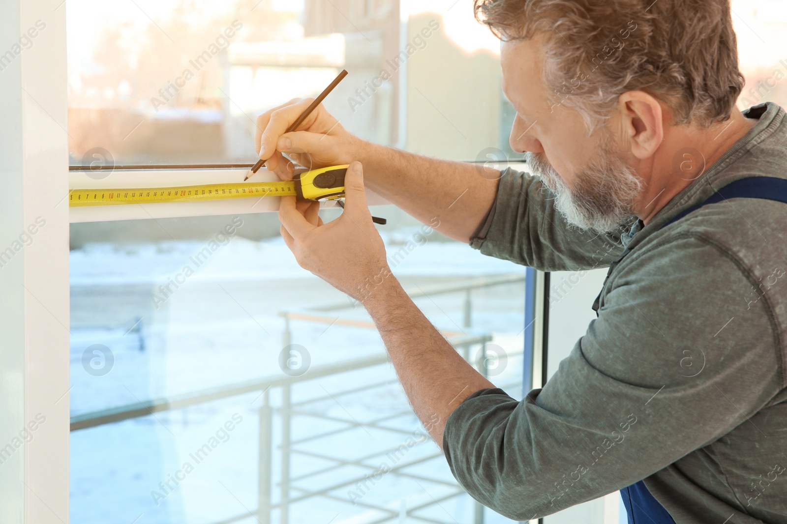 Photo of Service man measuring window for installation indoors