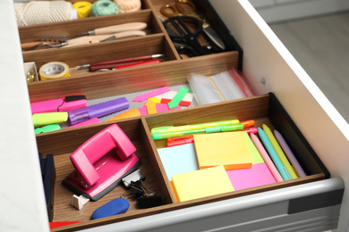 Photo of Stationery and sewing accessories in open desk drawer indoors, closeup