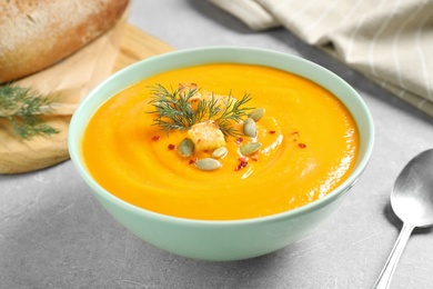 Photo of Delicious pumpkin soup in bowl on grey table