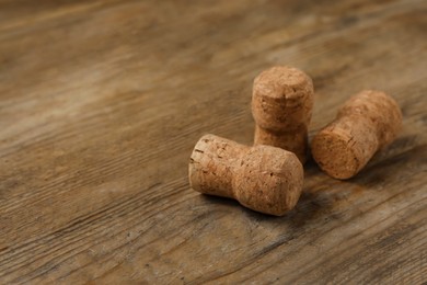 Photo of Sparkling wine corks on wooden table, closeup. Space for text