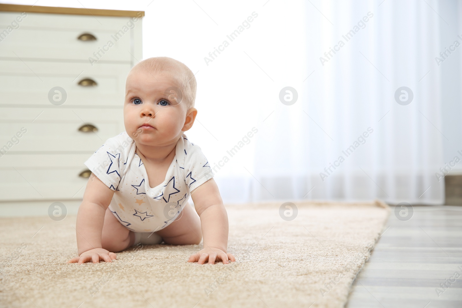 Photo of Cute little baby crawling on carpet indoors, space for text