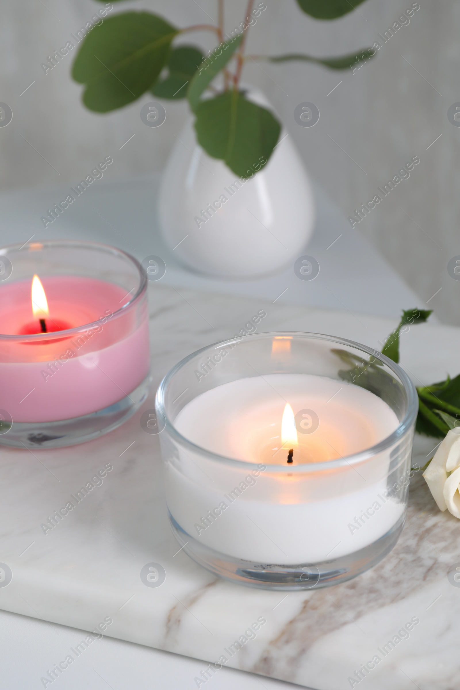 Photo of Burning candles in glass holders on white table