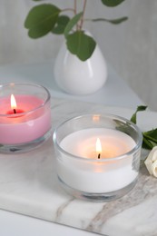 Photo of Burning candles in glass holders on white table