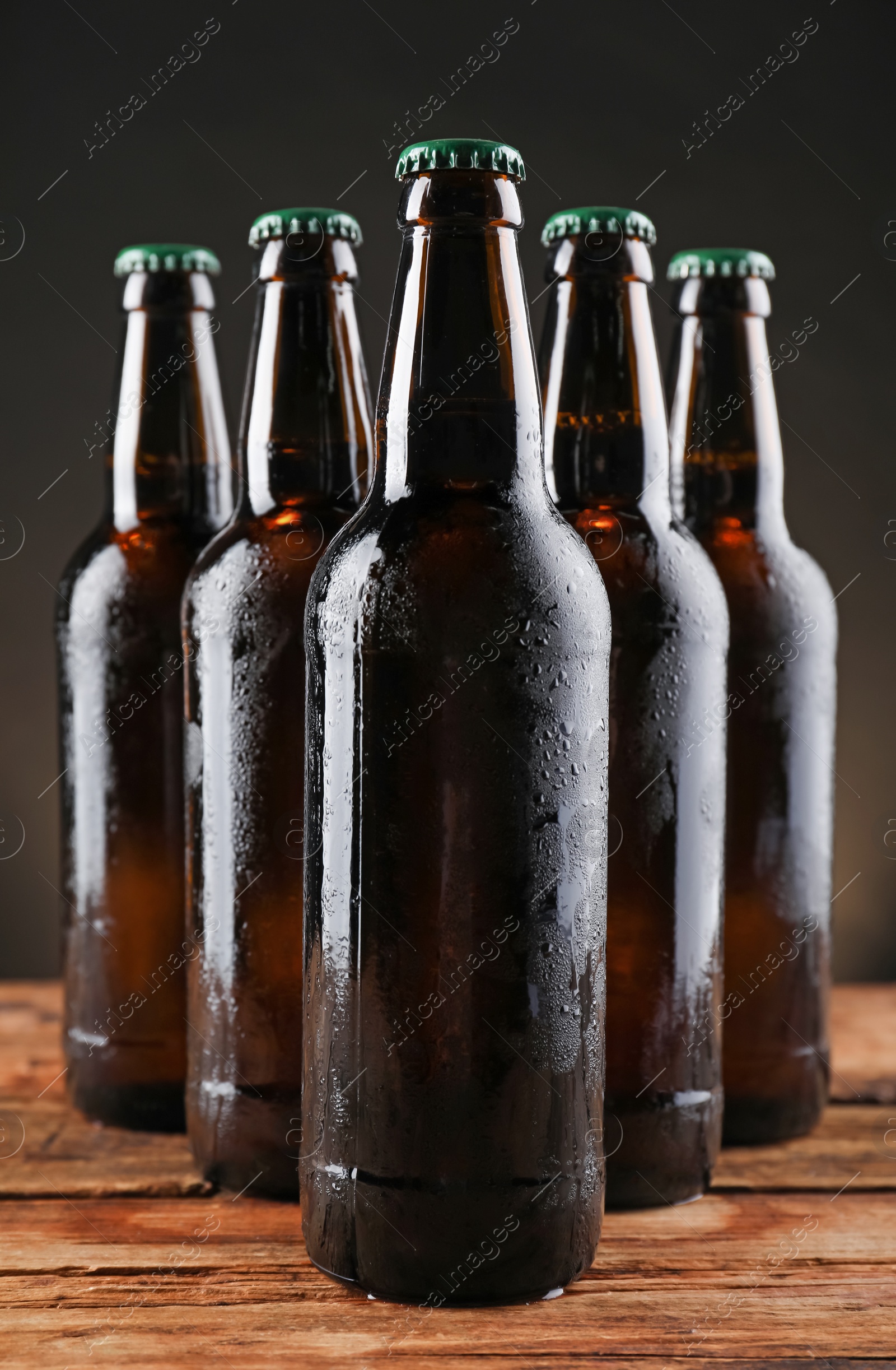 Photo of Many bottles of beer on wooden table against dark background
