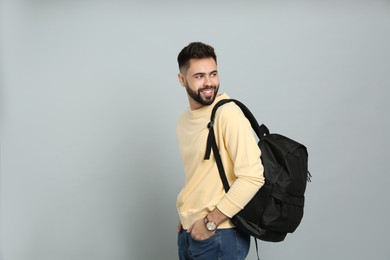 Photo of Young man with stylish backpack on light grey background. Space for text