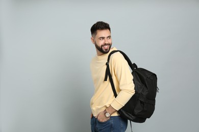 Young man with stylish backpack on light grey background. Space for text