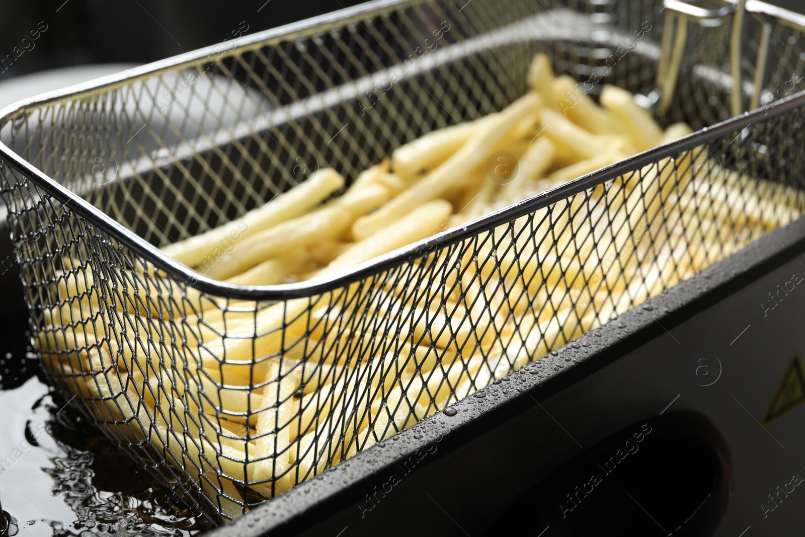 Photo of Cooking delicious french fries in hot oil, closeup