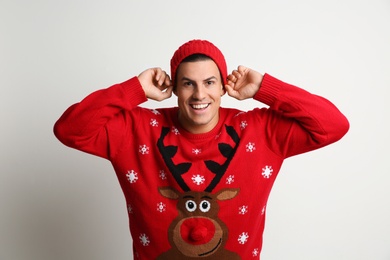 Happy man in Christmas sweater and hat on white background