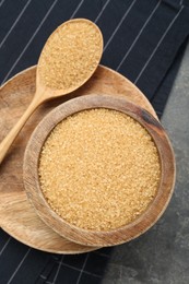 Photo of Brown sugar in bowl and spoon on grey table, top view