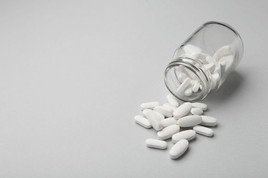 Vitamin pills and bottle on grey background, closeup. Space for text