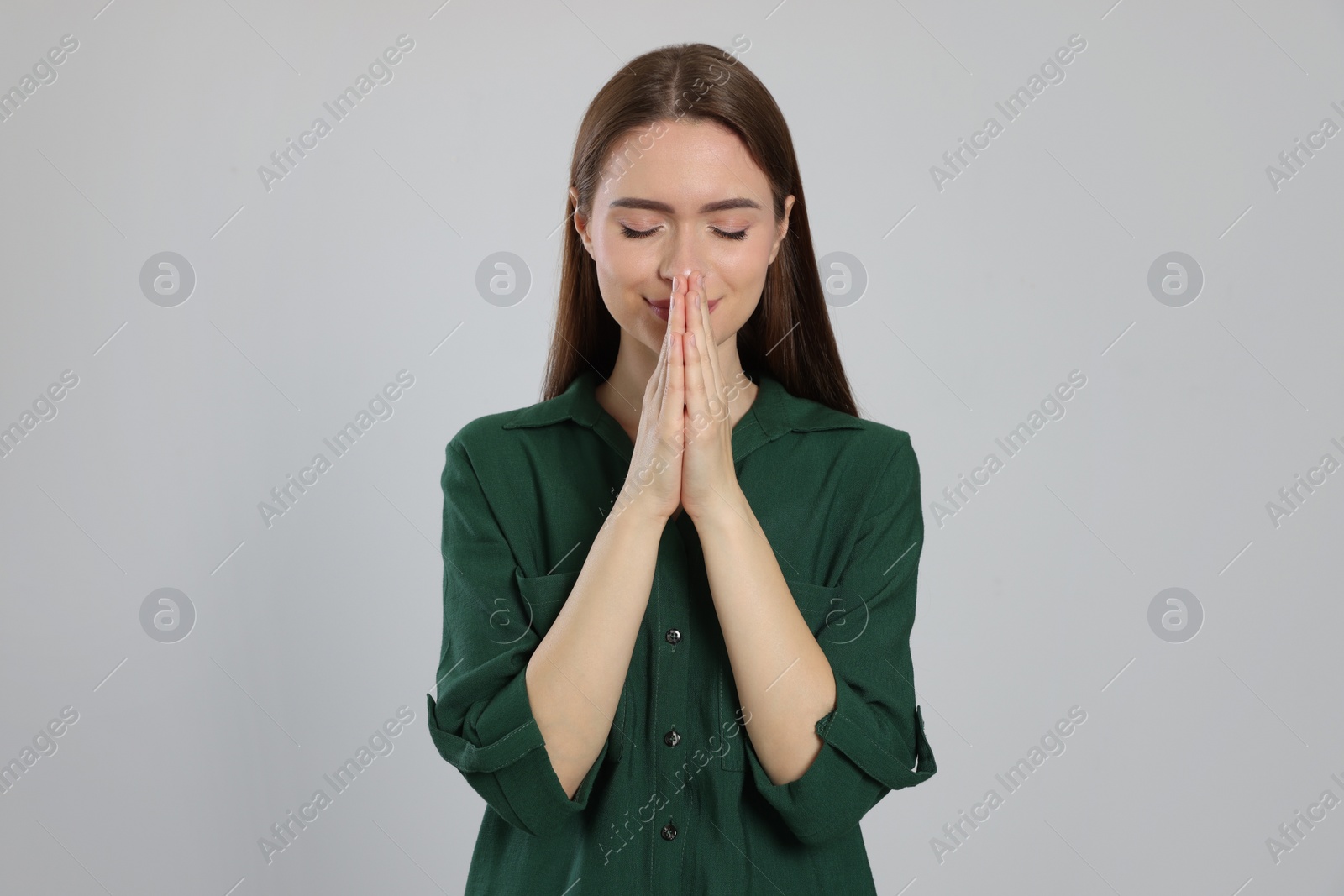 Photo of Woman with clasped hands praying on light grey background