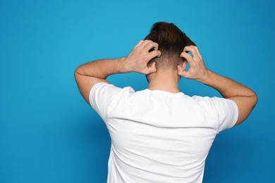 Photo of Young man scratching head on color background. Annoying itch