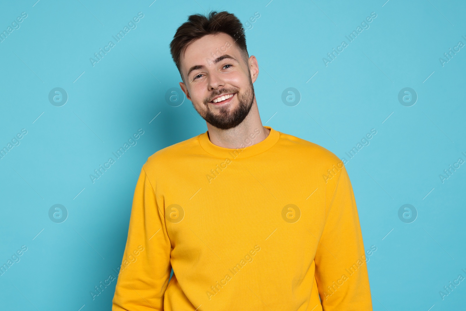 Photo of Handsome man in yellow sweatshirt on light blue background