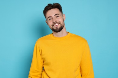 Handsome man in yellow sweatshirt on light blue background