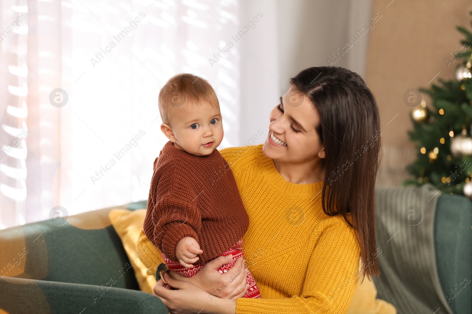 Photo of Happy young mother with her cute baby in room decorated for Christmas. Winter holiday