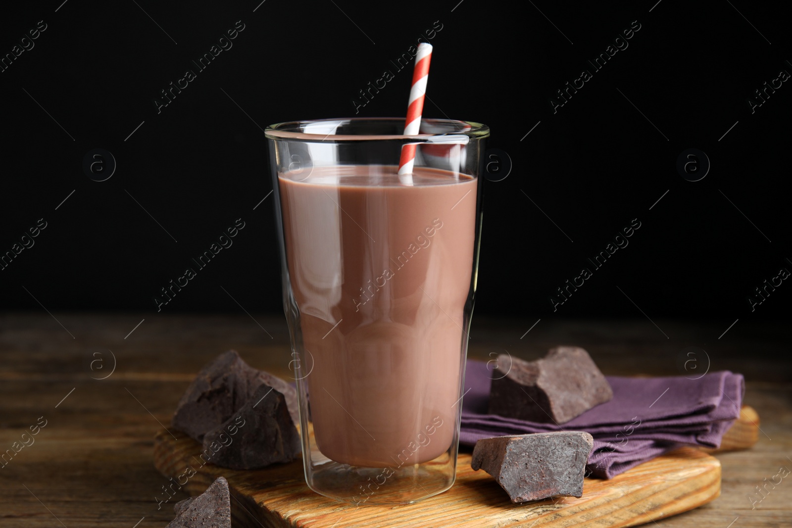 Photo of Delicious chocolate milk in glass on wooden table