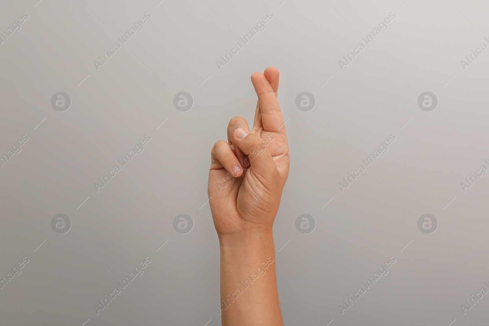 Photo of Teenage boy crossing fingers on light grey background, closeup