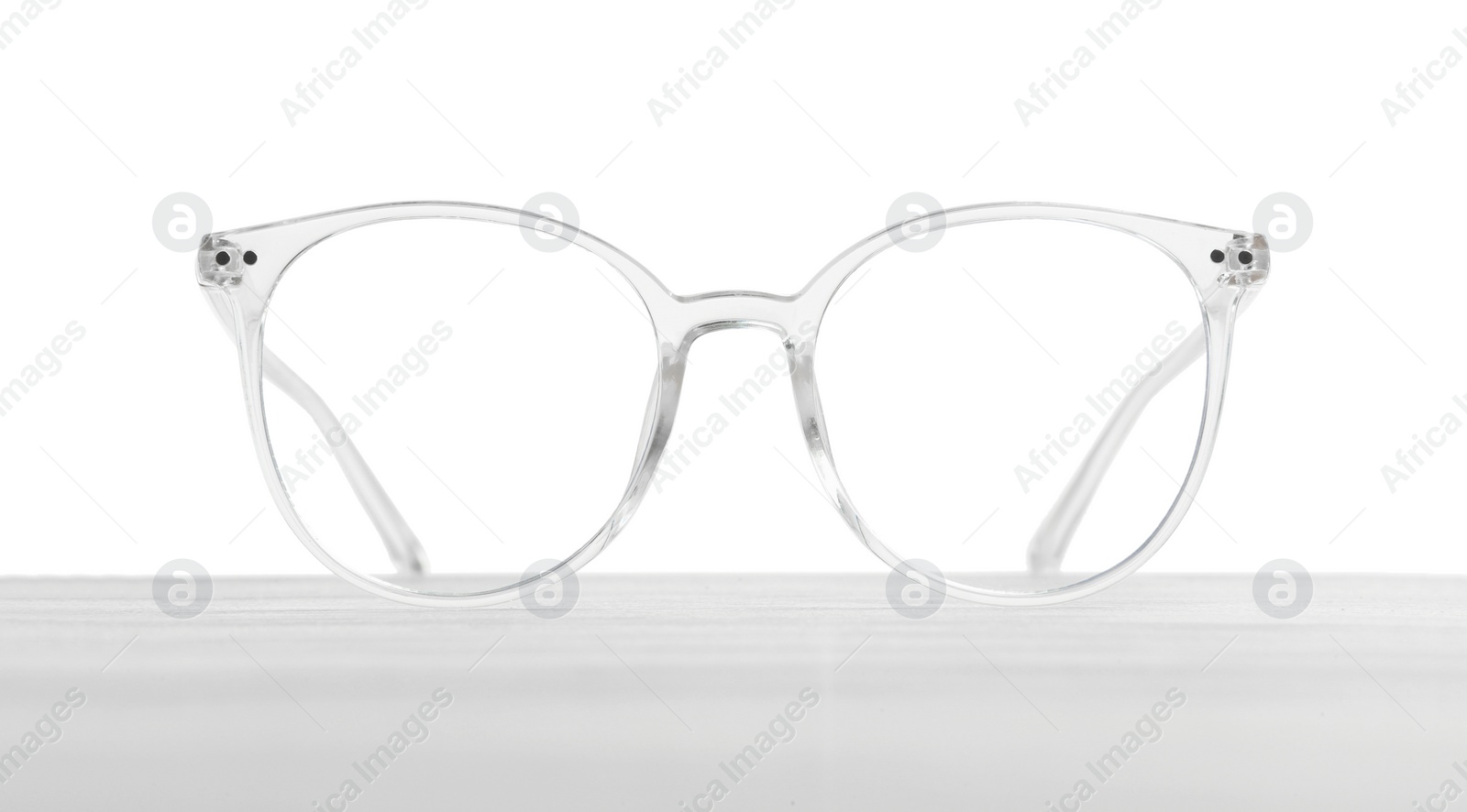 Photo of Stylish glasses with transparent frame on wooden table against white background