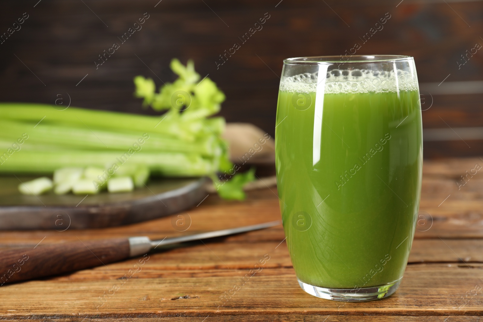 Photo of Glass of fresh celery juice on wooden table, closeup. Space for text