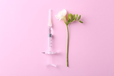 Photo of Cosmetology. Medical syringe and freesia flower on pink background, flat lay