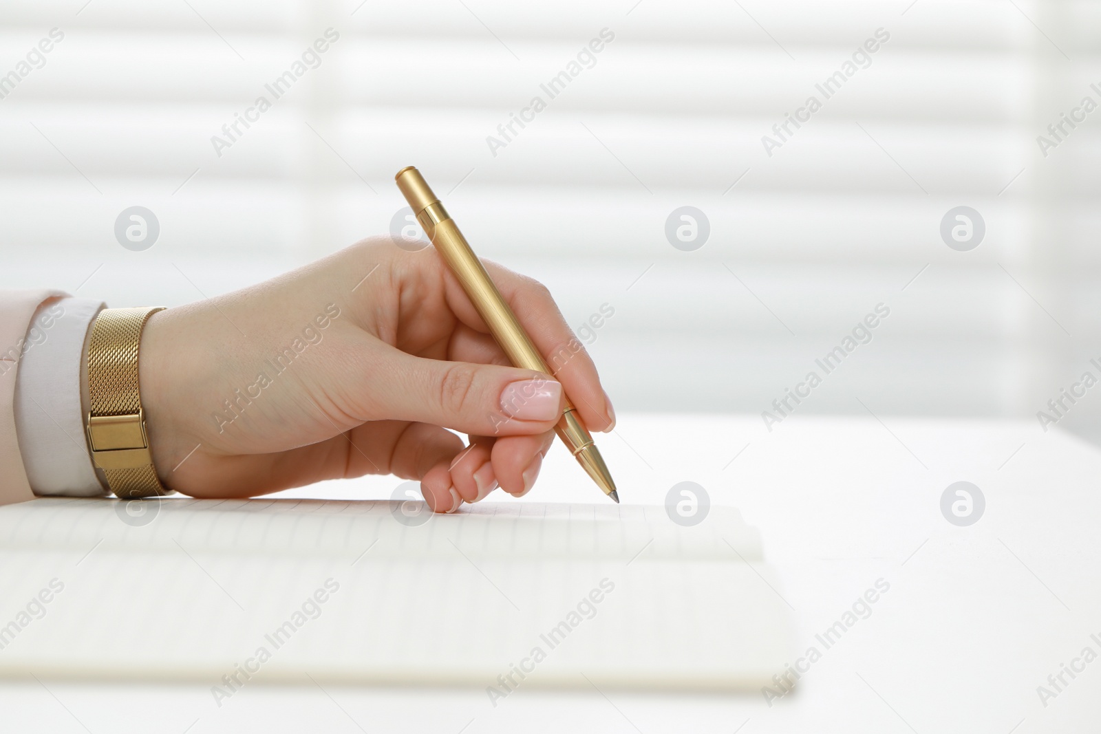 Photo of Woman writing in notebook at white table, closeup