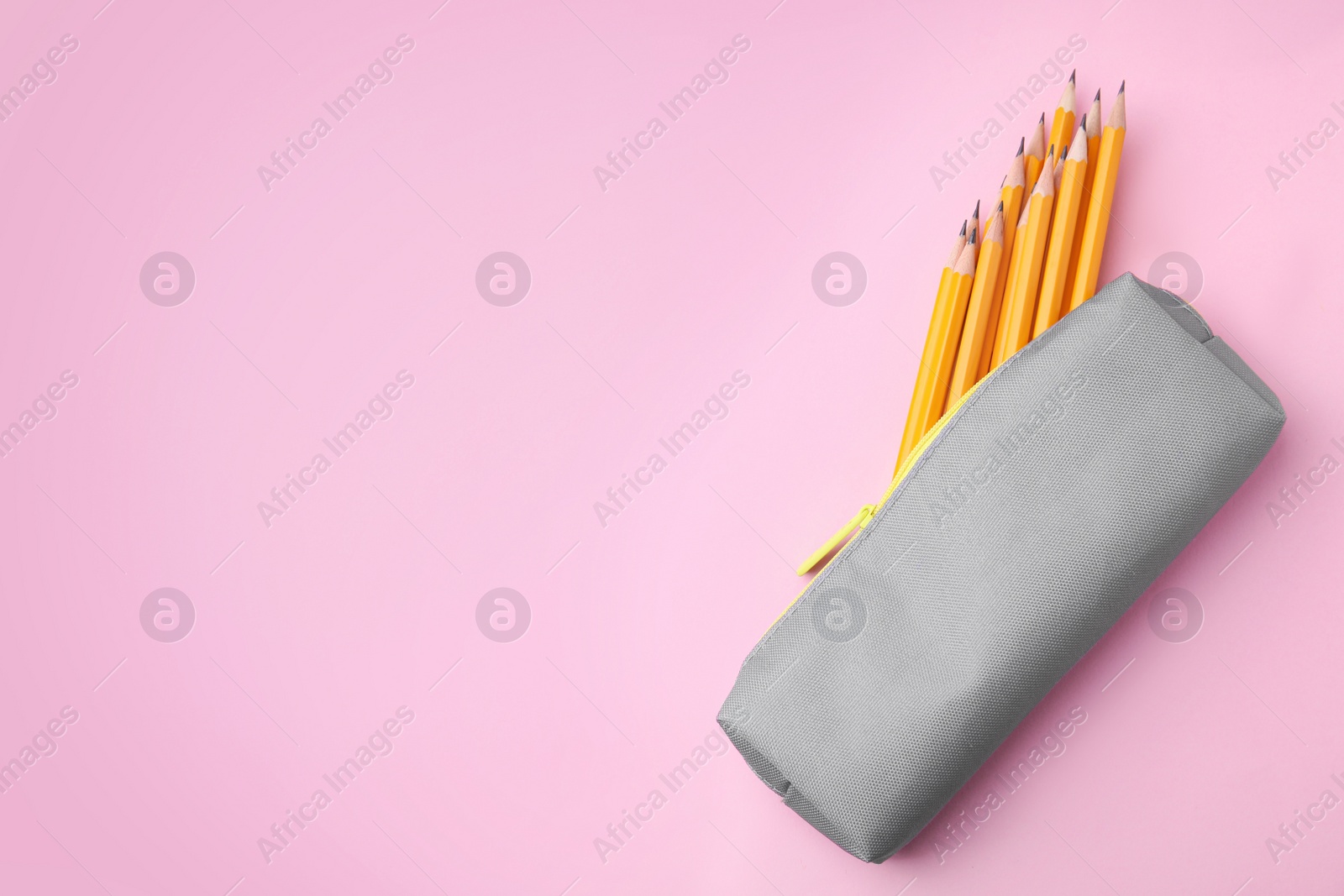 Photo of Many sharp pencils in pencil case on pink background, top view. Space for text