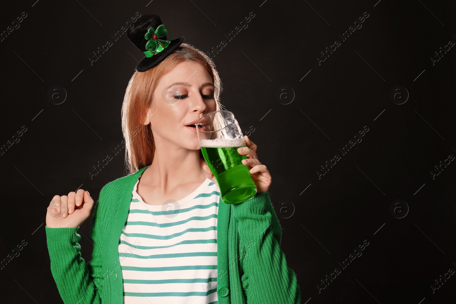 Photo of Young woman with green beer on black background, space for text. St. Patrick's Day celebration