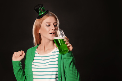 Photo of Young woman with green beer on black background, space for text. St. Patrick's Day celebration
