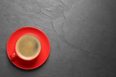 Photo of Aromatic coffee in red cup on black background, top view. Space for text