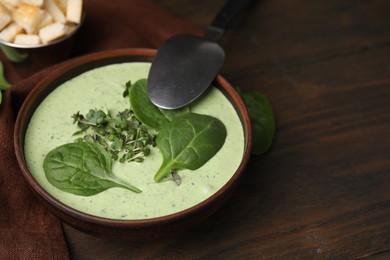 Photo of Delicious spinach cream soup served on wooden table. Space for text