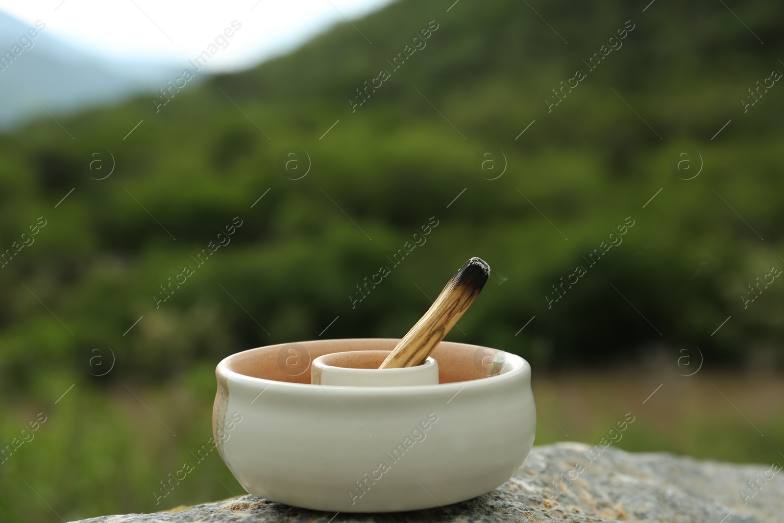 Photo of Burnt palo santo stick on stone surface in high mountains, closeup