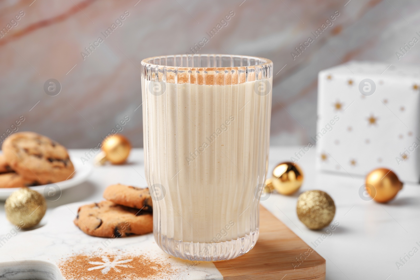 Photo of Glass of delicious eggnog with cinnamon on white table