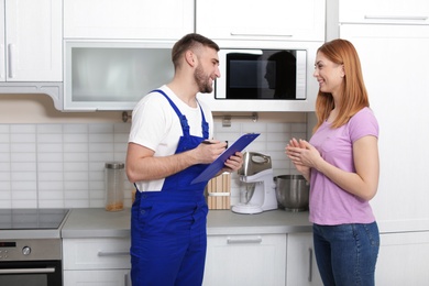 Photo of Housewife and repairman near microwave oven in kitchen