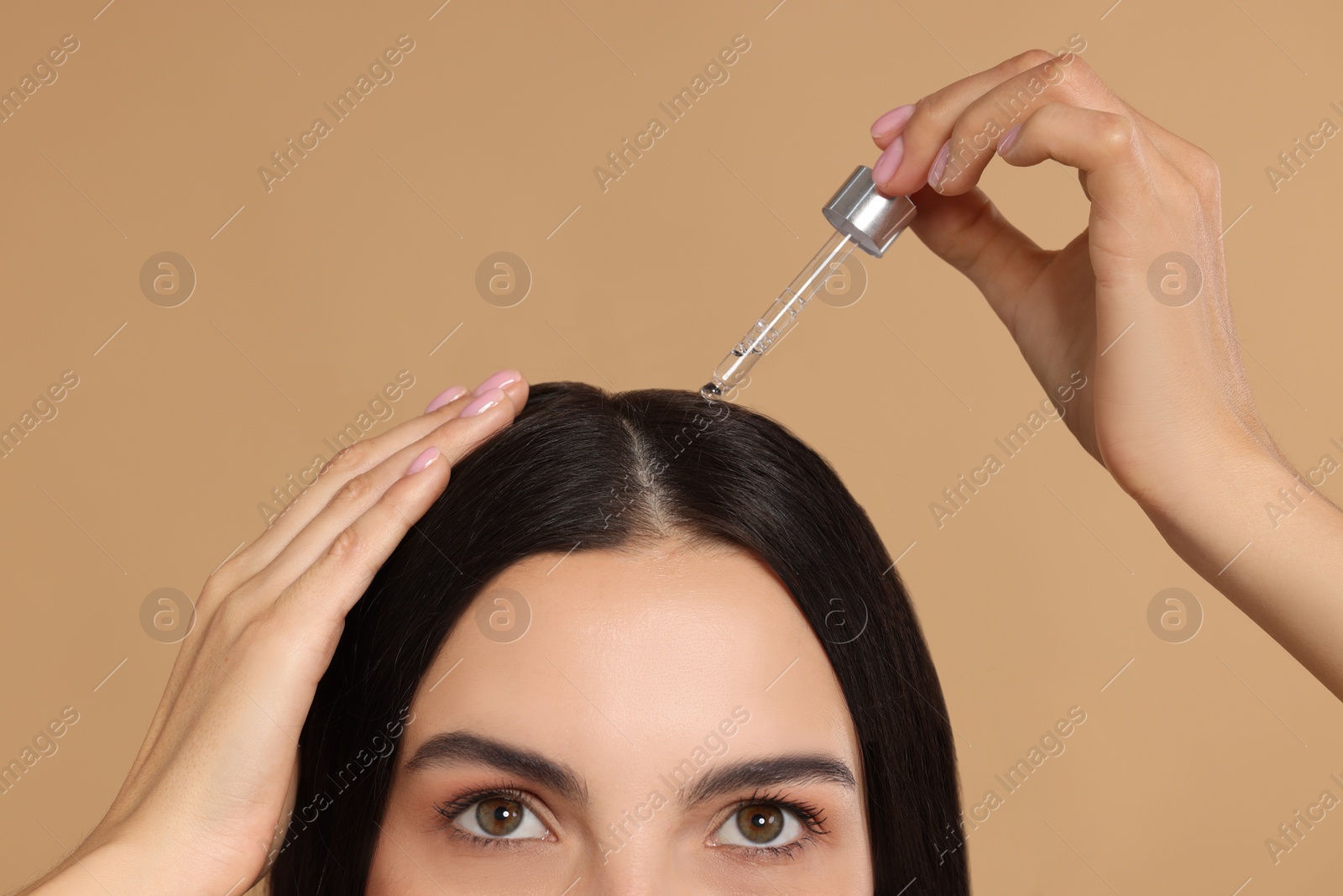 Photo of Woman applying hair serum on beige background, closeup. Cosmetic product