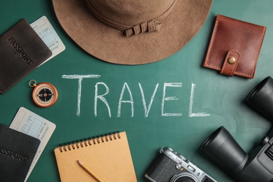 Photo of Flat lay composition with different tourist objects and word TRAVEL on color background
