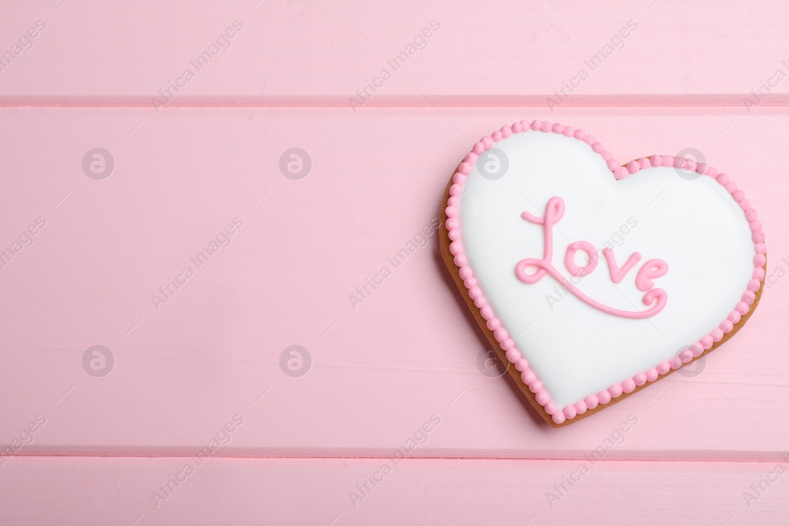Photo of Valentine's day cookie with word Love on pink table, top view. Space for text